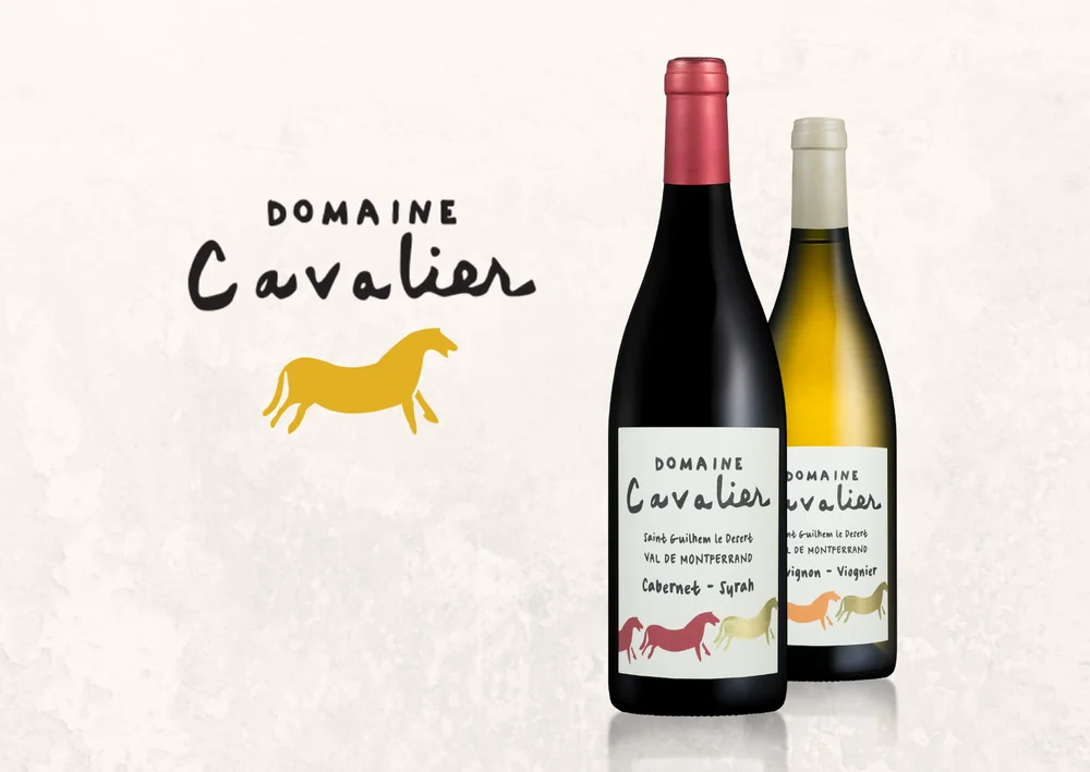 Visuel de marque de la gamme IGP : logo 'Domaine Cavalier' (cheval jaune) a gauche, et les deux bouteilles Domaine Cavalier rouge (Cabernet-Syrah) et blanc (Sauvignon-Viognier) en situation. Correspond exactement a la ligne IGP Saint-Guilhem-le-Desert de ce domaine.