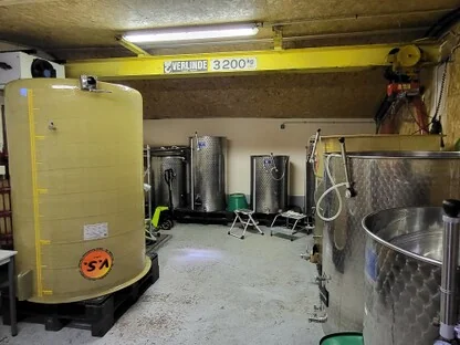 Chai a barriques : alignement de futs de chene dans un caveau voute, eclairage chaud. Belle image de cave valorisante.