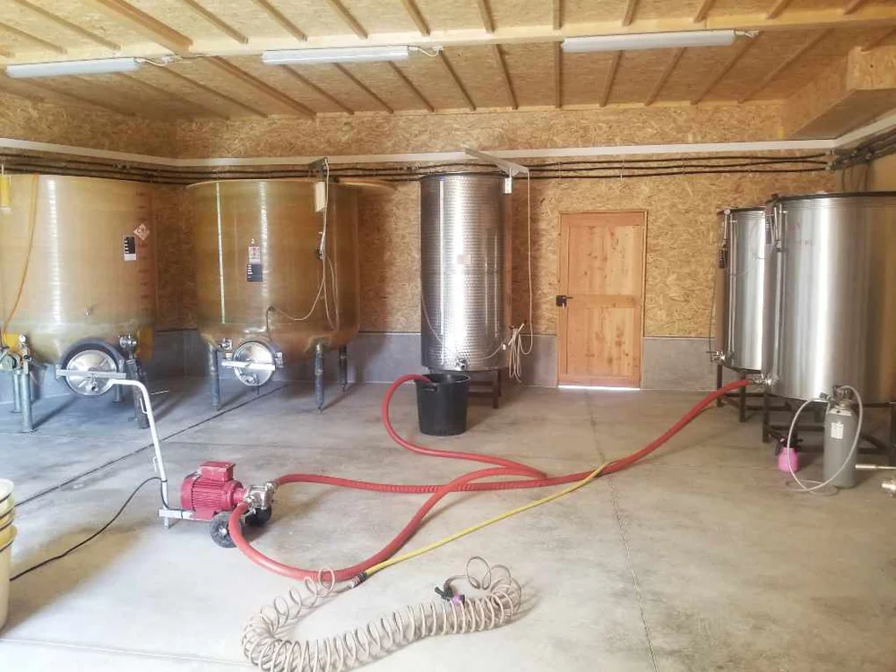 Interieur du nouveau chai en bois : cuves fibre et inox, charpente bois apparente. Vue d'ensemble de la cave de vinification.