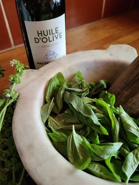 Bouteille d'huile d'olive du domaine (Huile d'Olive) avec mortier de pierre et feuilles d'olivier. Joli packshot lifestyle du produit l'Olivette.